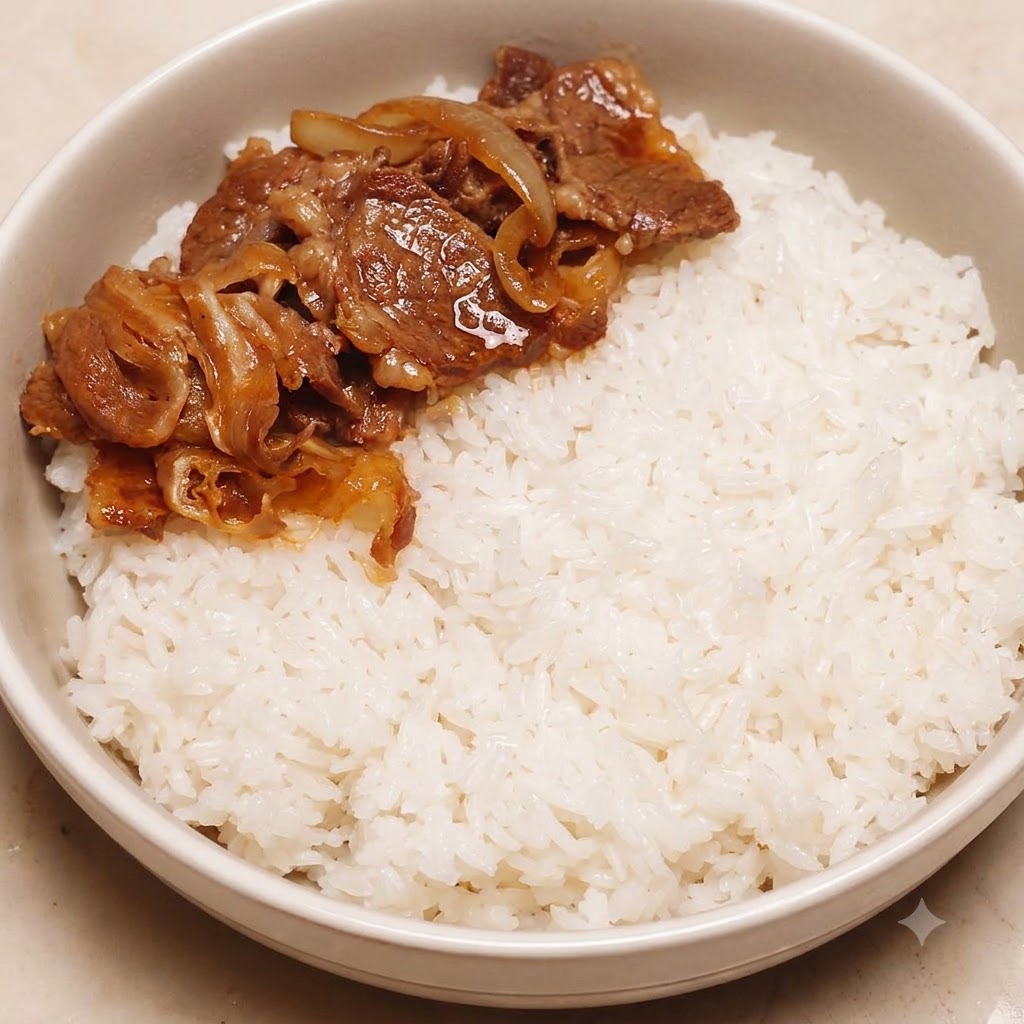 白ご飯を盛った丼ぶりの片側に、調理した牛肉と玉ねぎがきれいに盛り付けられている様子。