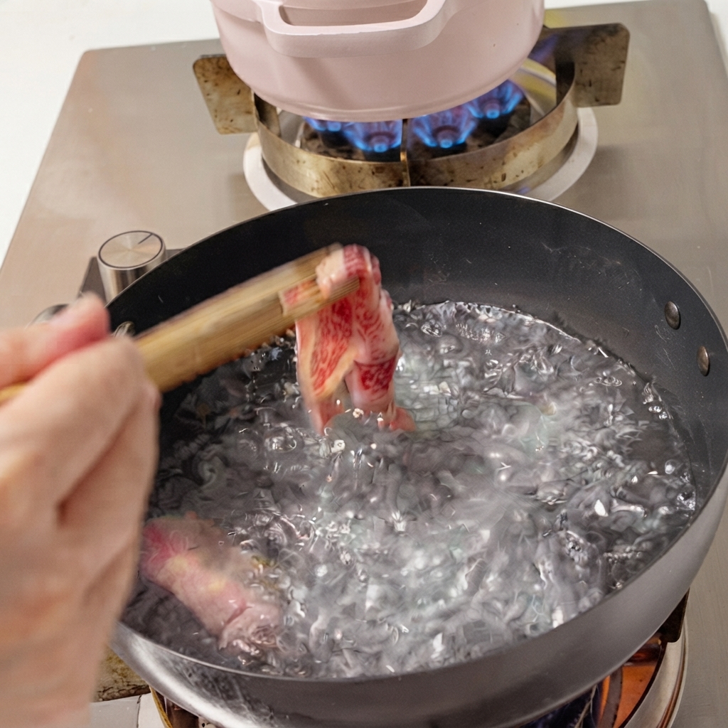 箸を使って沸騰したお湯の鍋に投入される新鮮な薄切り牛肉。