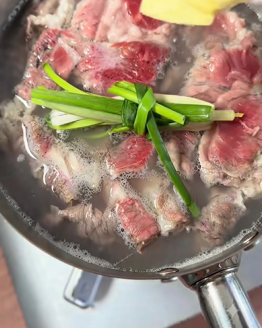 牛肉を茹でている鍋に、結んだネギと生姜の薄切りが浮いている様子。