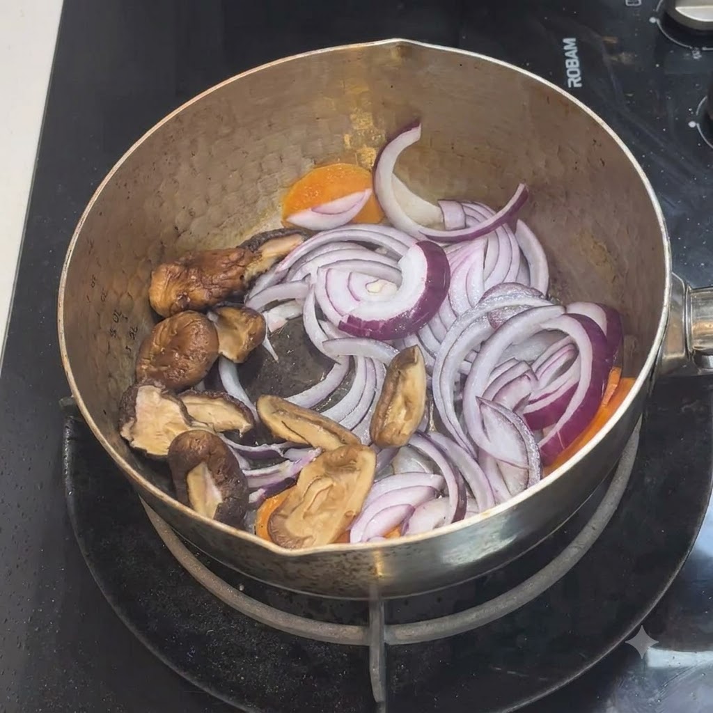 玉ねぎとにんじんが入った鍋に、スライスしたしいたけが加えられている様子。