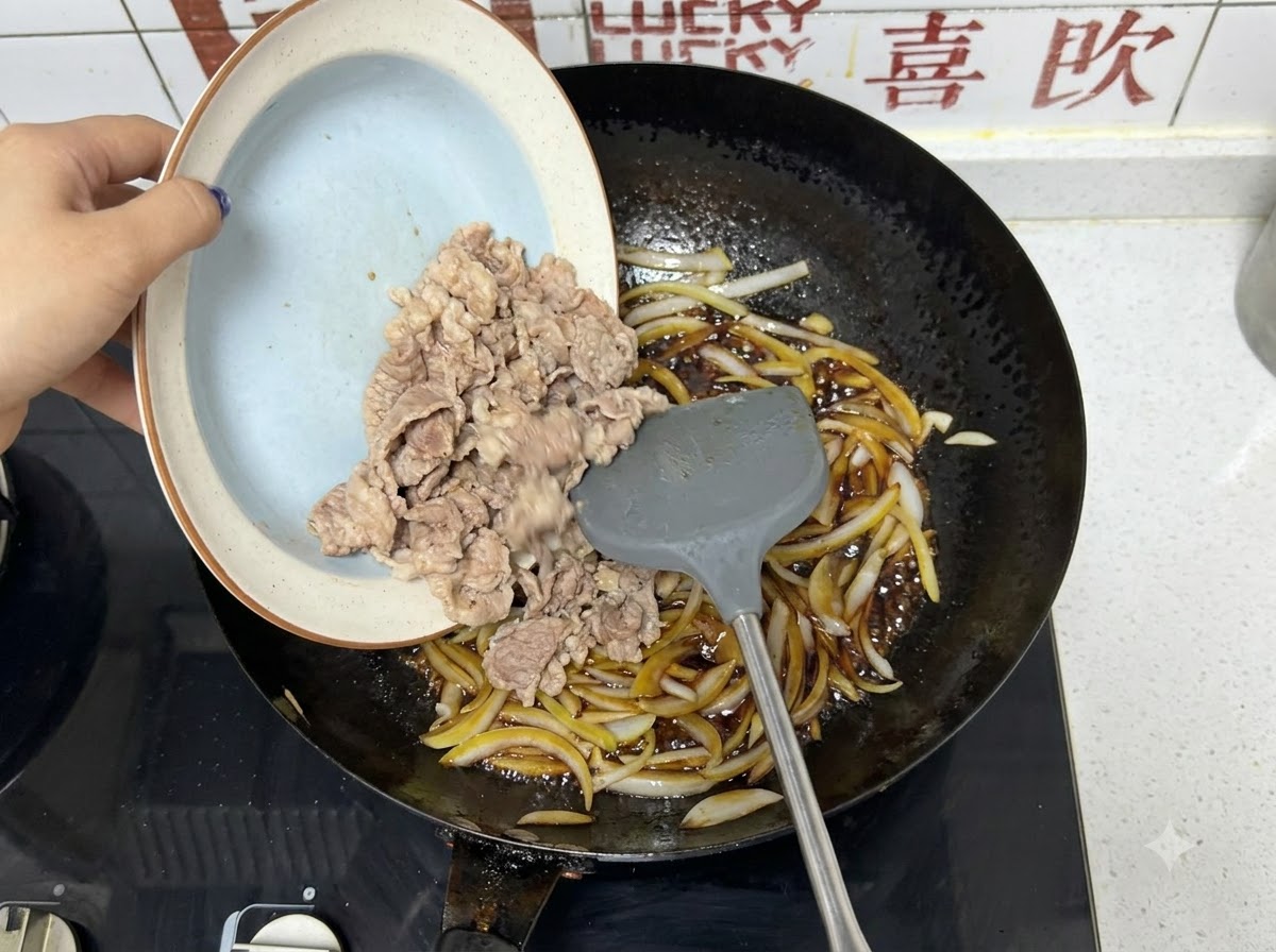 湯通しした牛肉をプレートから玉ねぎと黒いたれの入った中華鍋に入れる様子。
