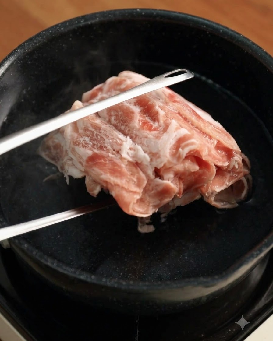 金属製のトングを使い、沸騰したお湯に冷凍の牛薄切り肉を入れている様子。
