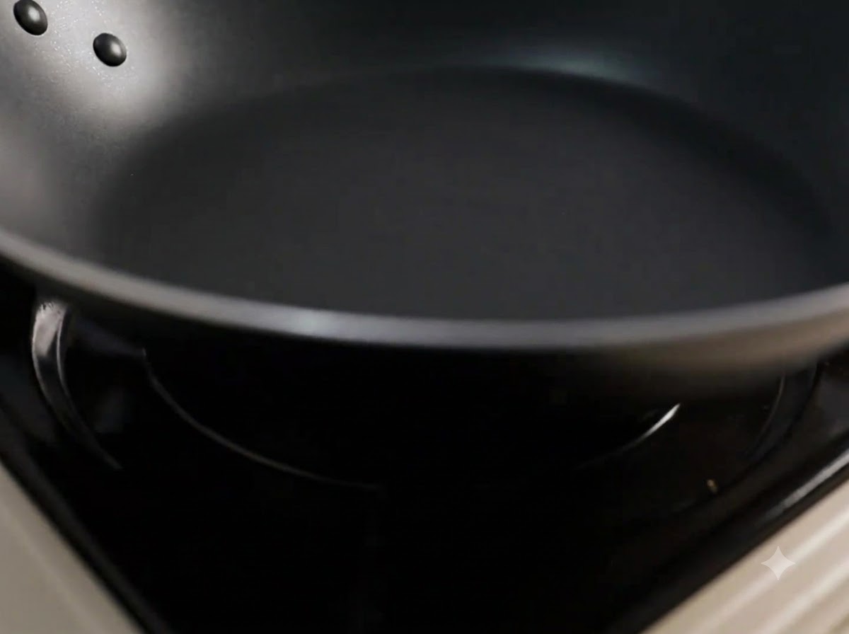 熱した黒いフライパンに調理油を注ぎ入れている様子。