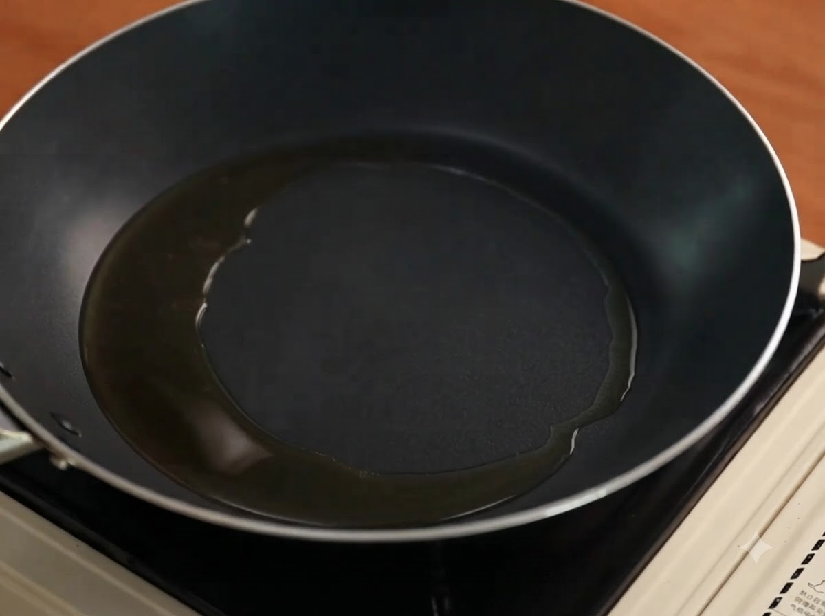 油をひいたフライパンで、薄切りにした赤玉ねぎが炒められている様子。