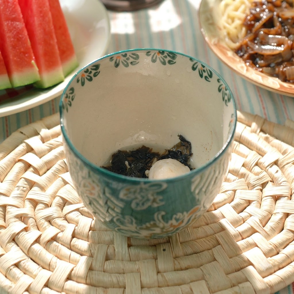 模様のある陶器のスープボウルに盛り付けられた、茹でた豚肉団子とわかめ。