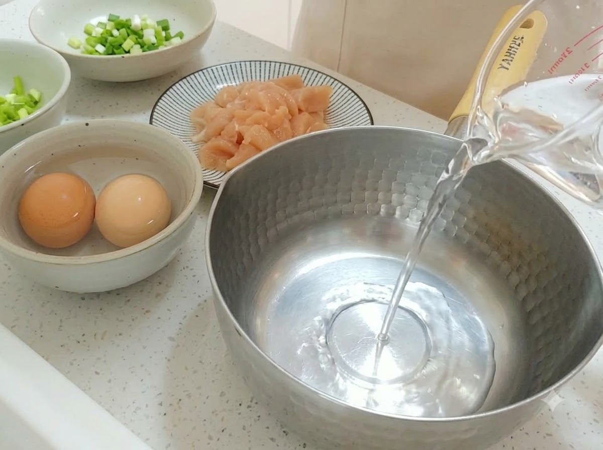 計量カップから鍋に水を注ぐ様子