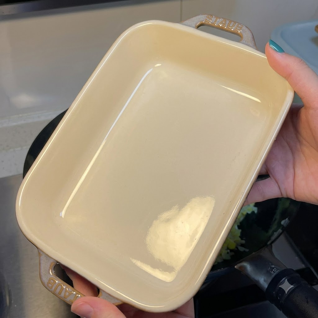 卵チャーハンの入った中華鍋の上に、白い長方形のセラミック製耐熱皿をかざしている人物。