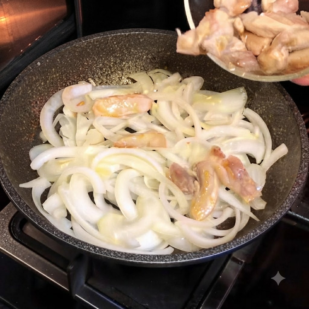 スライスした白玉ねぎが入った熱いフライパンに、小さなガラスボウルから半調理の鶏肉を移している様子。