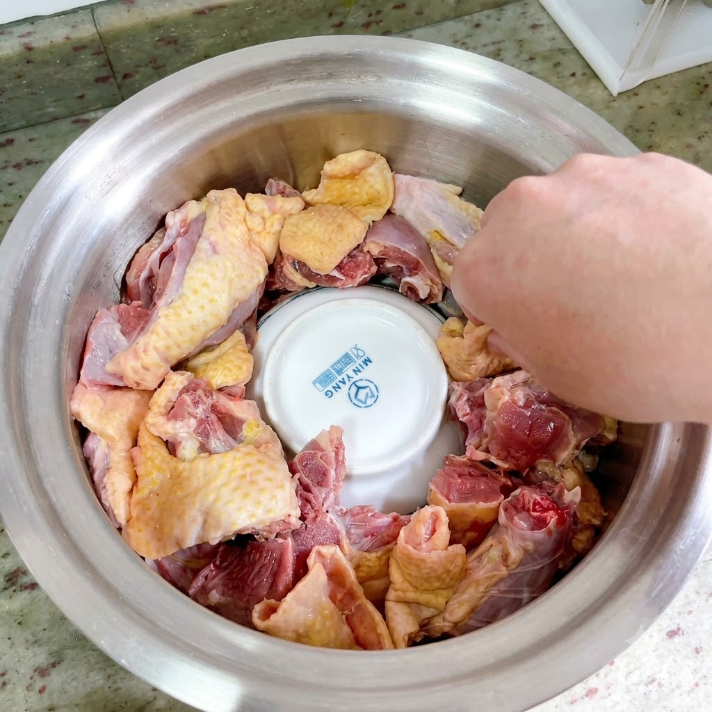 金属鍋の中の逆さにした陶器のお椀の周りに、生のアヒル肉のピースがきれいに円形に並べられている。