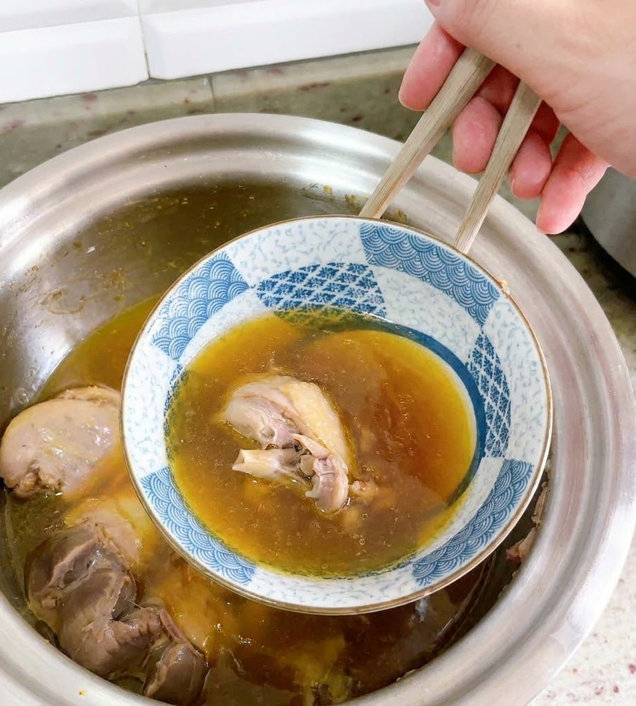 アヒルのスープの中から、箸を使って逆さにした陶器のお椀が慎重に持ち上げられているところ。