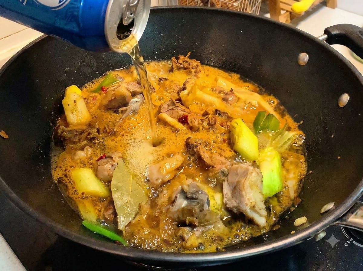 香ばしく炒められた鴨肉とソースが入った中華鍋に、ビールの缶からビールが注がれている様子。