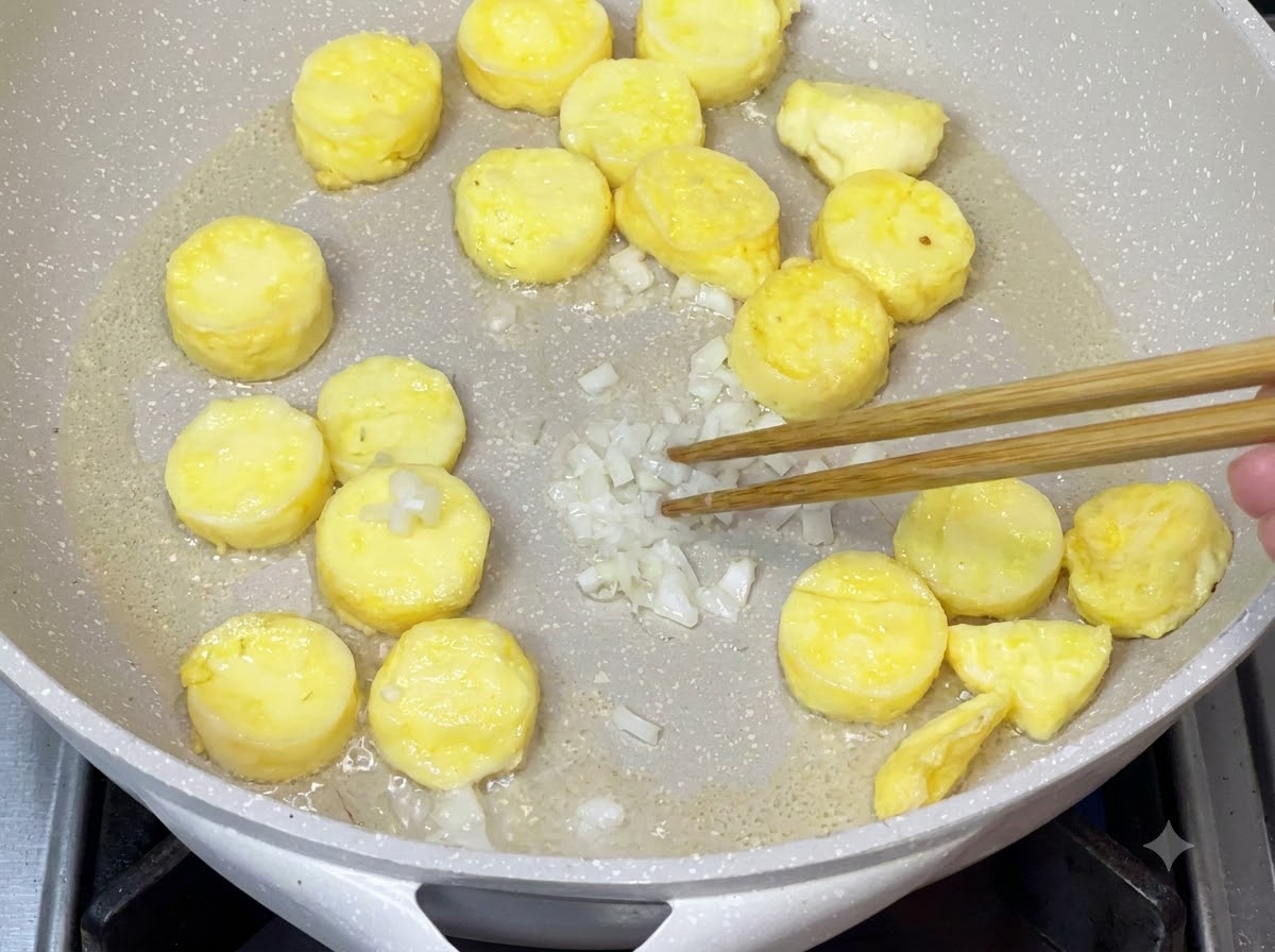 余分な油を取り除いた後、香り高い風味を引き出すために刻んだ青ねぎがフライパンで炒められているところ。