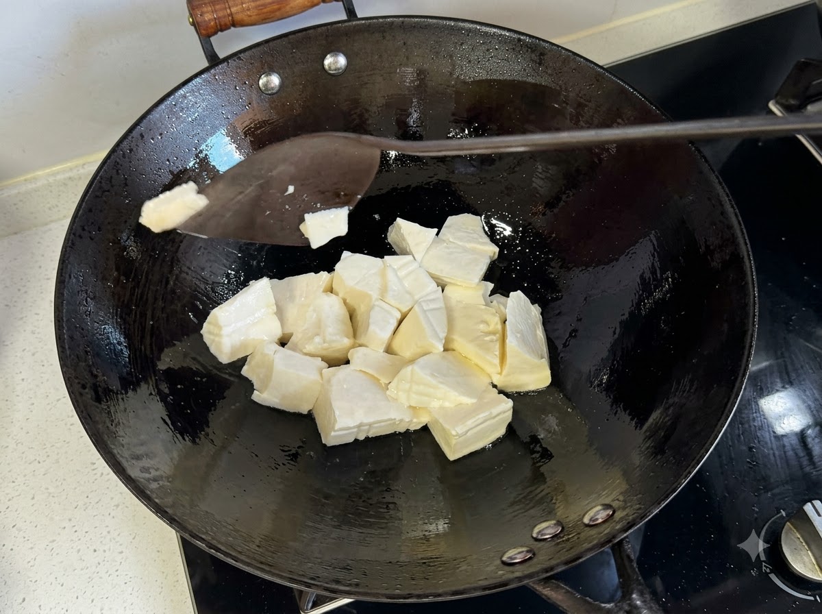 熱したフライパンの中で、ヘラを使って柔らか豆腐を切り分けている様子。