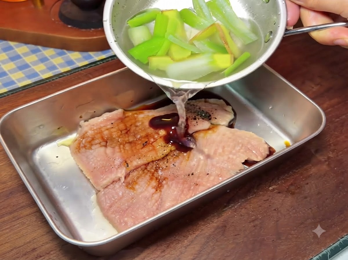 金属製のボウルの中で豚肉に調味液を注ぎ入れている様子。