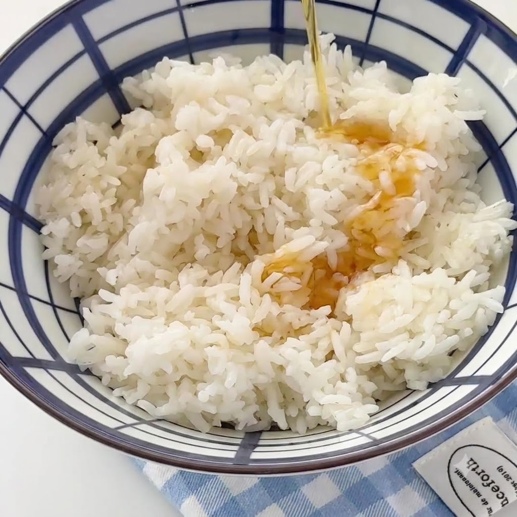 炊いた白米が入った大きなボウルに、ごま油を回しかけている様子。