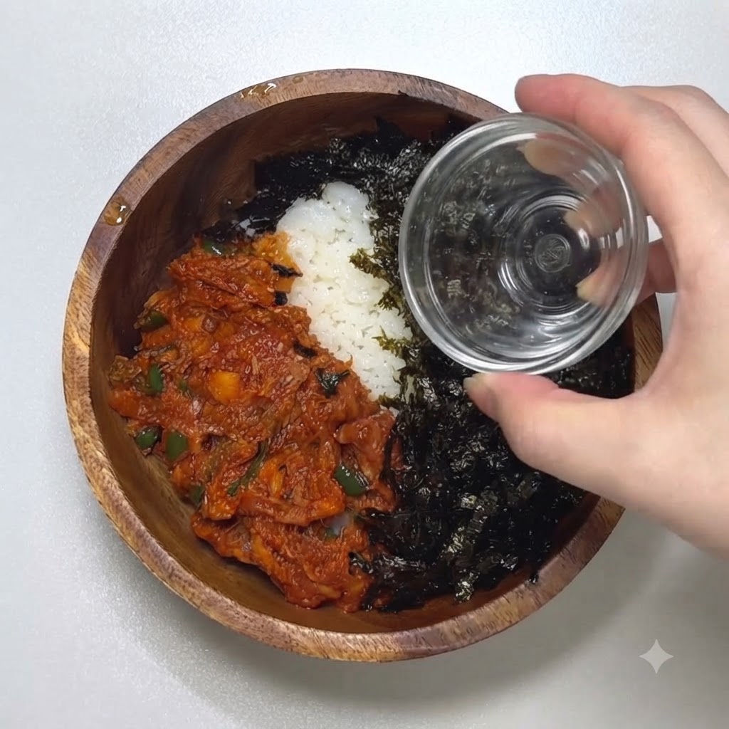 スパイシーツナともみ海苔がのった丼に、いりごまを振りかけているアップ画像。