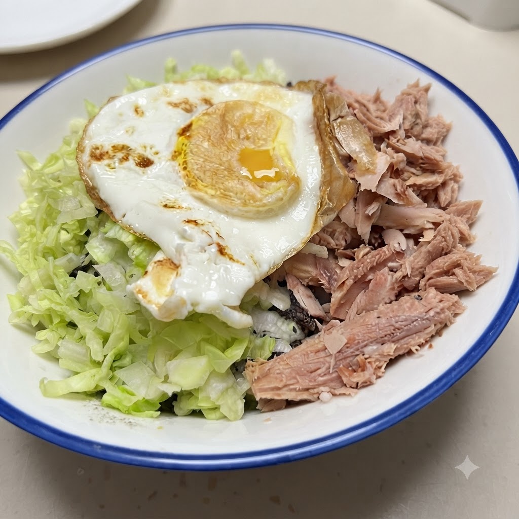 ご飯、ツナ、野菜、目玉焼きがのった完成した丼ぶり