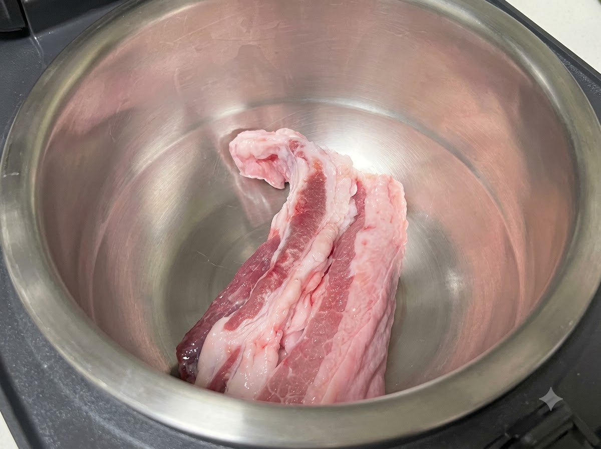 炊飯器の内釜に入った生鮮の豚バラ肉。