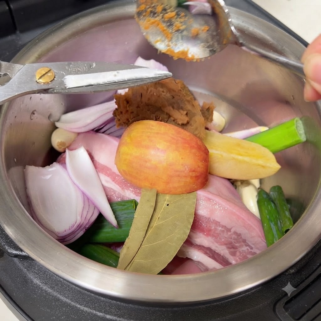 炊飯器の具材の上に韓国味噌(テンジャン)をスプーンで加えている様子。