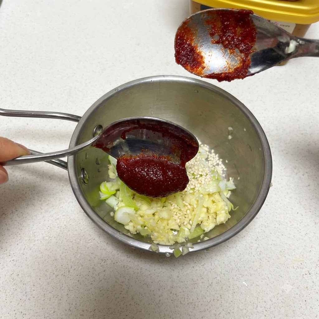 にんにくとごまが入ったボウルにコチュジャンを加えている様子。