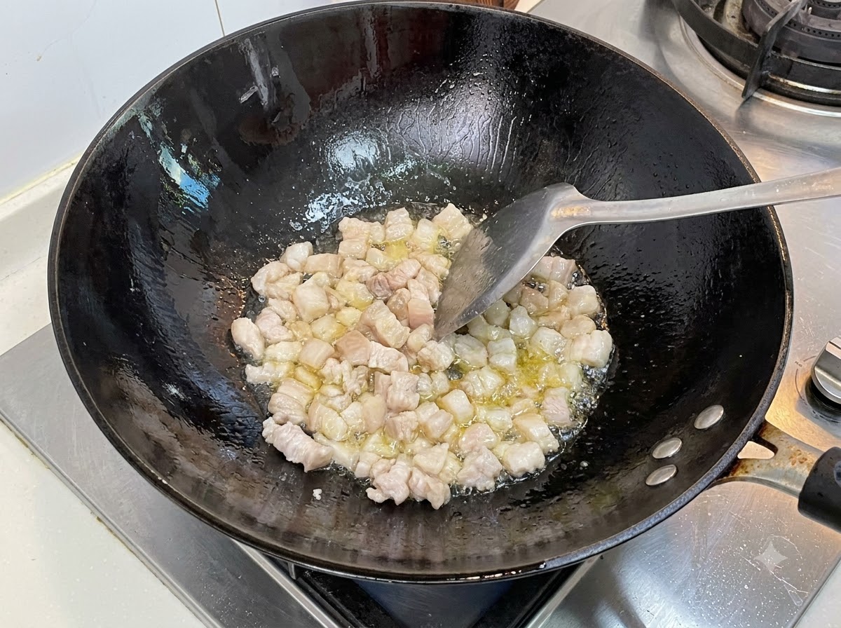 切塊肥豬肉在熱黑鍋中加油用鍋鏟翻炒。