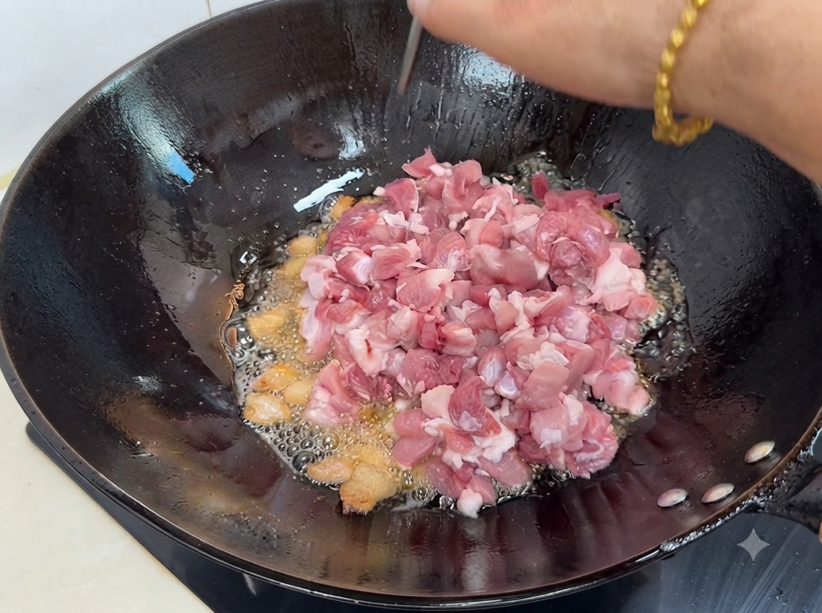 新鮮切丁瘦豬肉放入含有煉出油脂與香料的熱鍋中。
