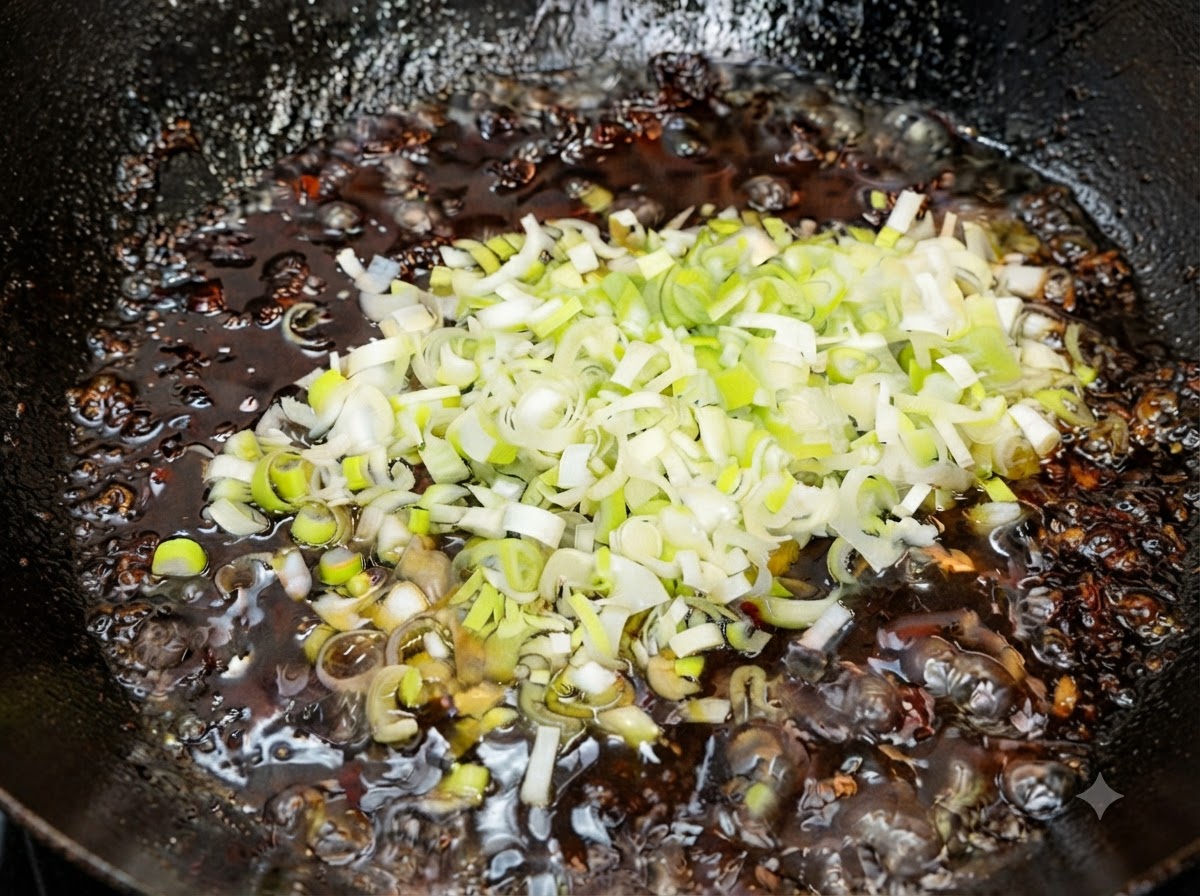 切碎的新鮮綠青蔥在熄火後拌入熱騰騰完成的炸醬中。
