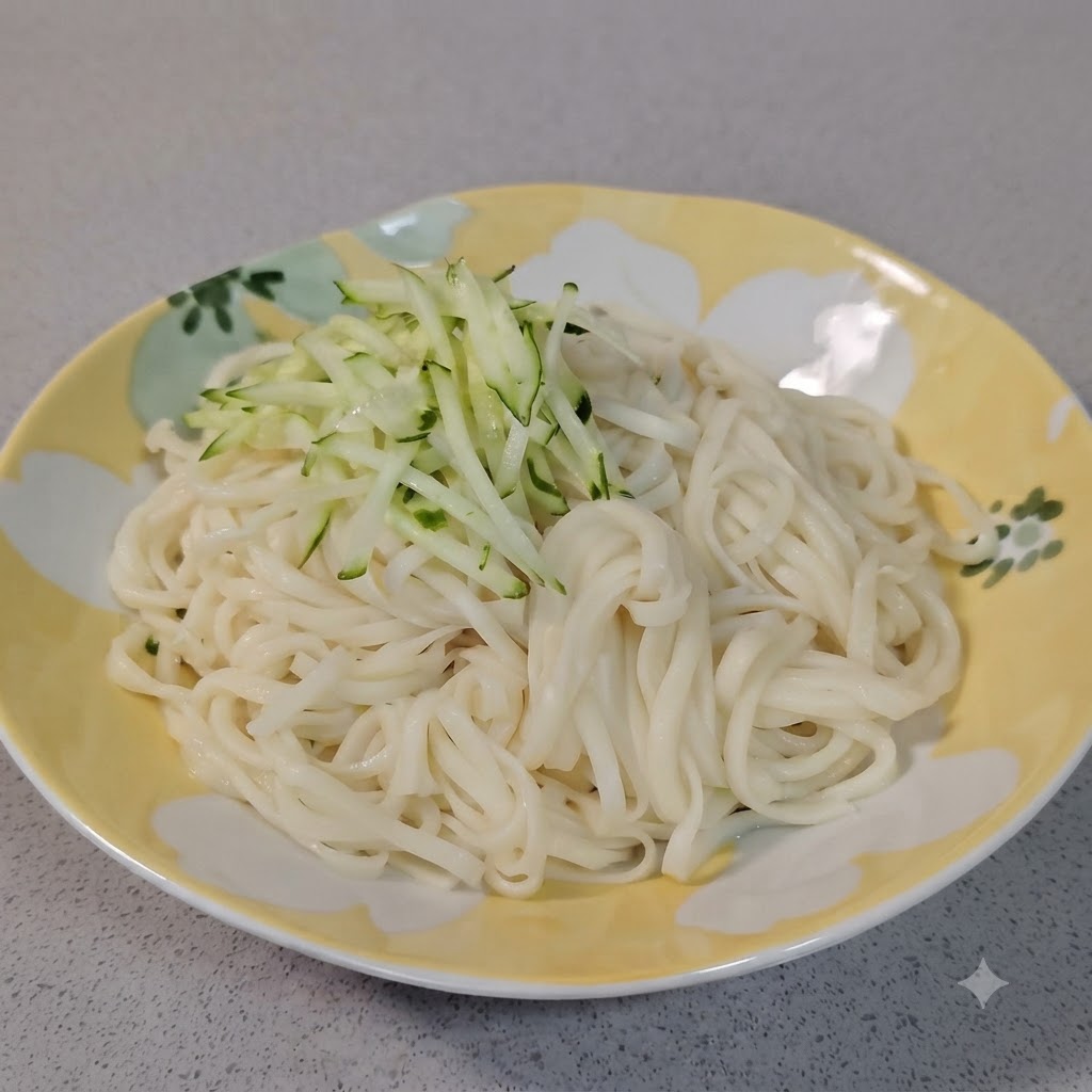 装飾されたお皿に盛られた茹でた白い麺の上に、新鮮な緑色の千切りきゅうりが山盛りでトッピングされているところ。