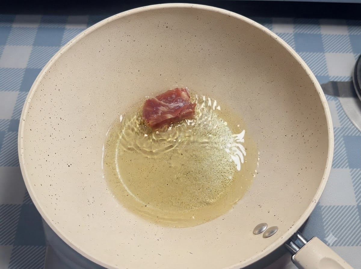 箸を使って、熱した油が入った白いフライパンの中にポークリブを1片ずつ入れている様子。