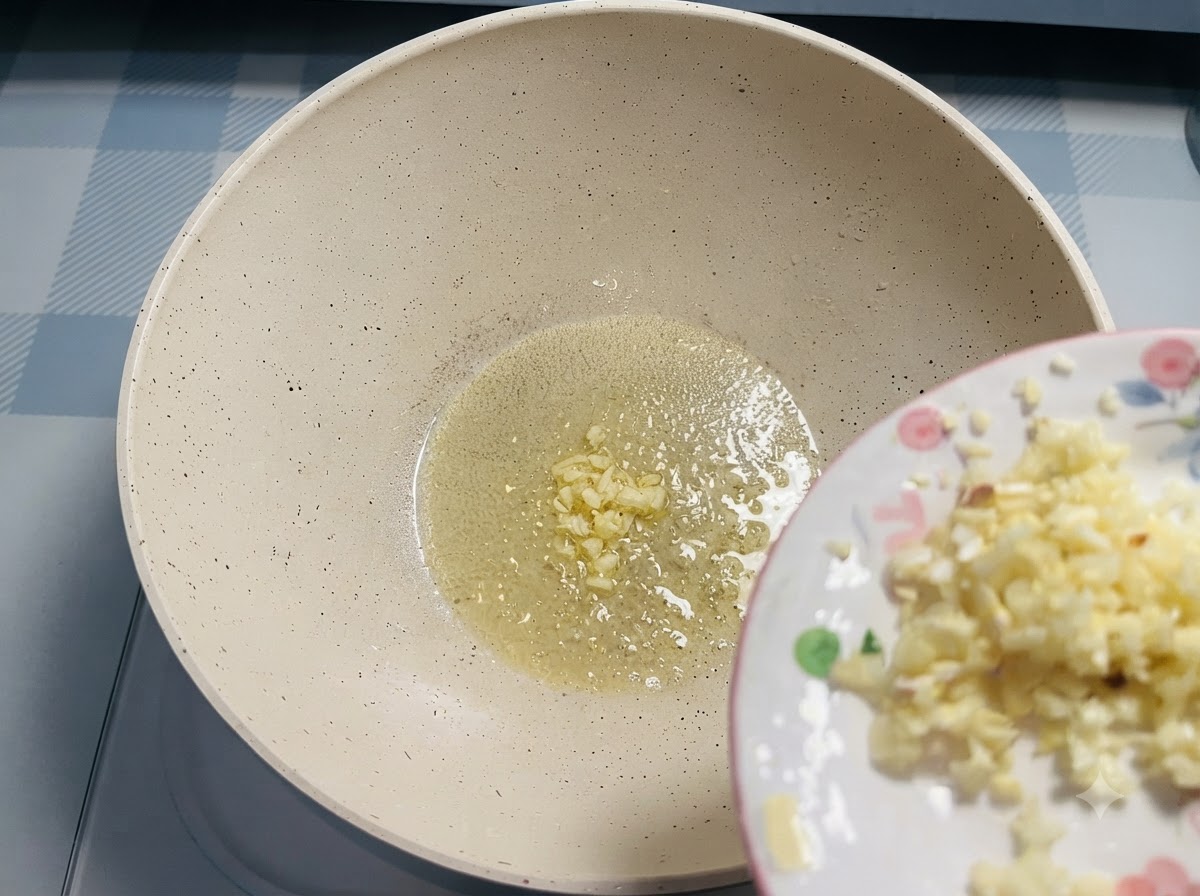 小皿から、フライパンで溶けたバターの中に刻みニンニクが滑り落ちている様子。