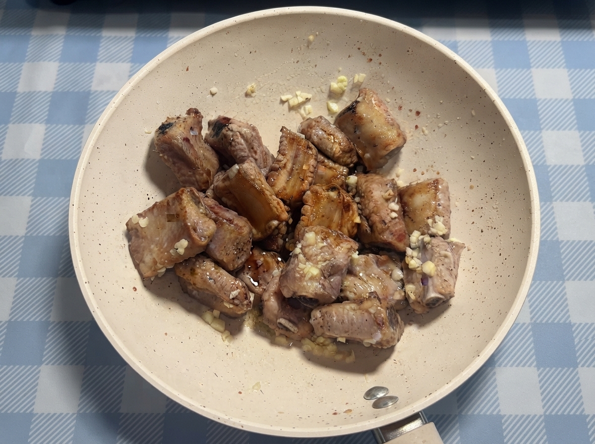 最終的な和え作業の前に、フライパンの中でソースと蜂蜜がポークリブにかけられている様子。
