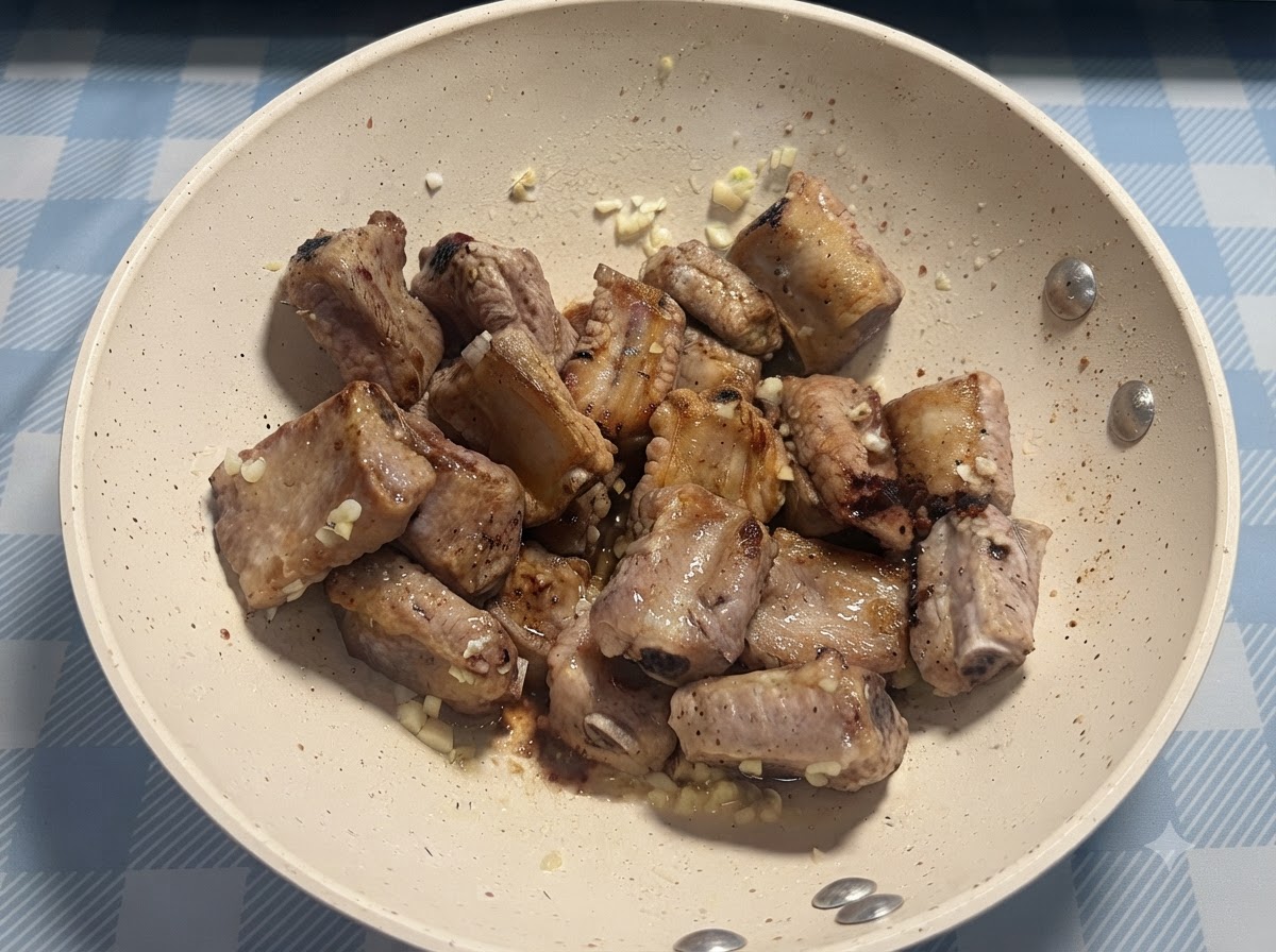 フライパンで揚げ焼きにされたポークリブの上に、少量の塩が直接振りかけられている様子。