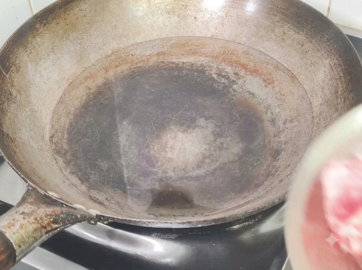 中華鍋に冷水、生姜、料理酒と一緒に入れられ、下茹でされる豚スペアリブ。