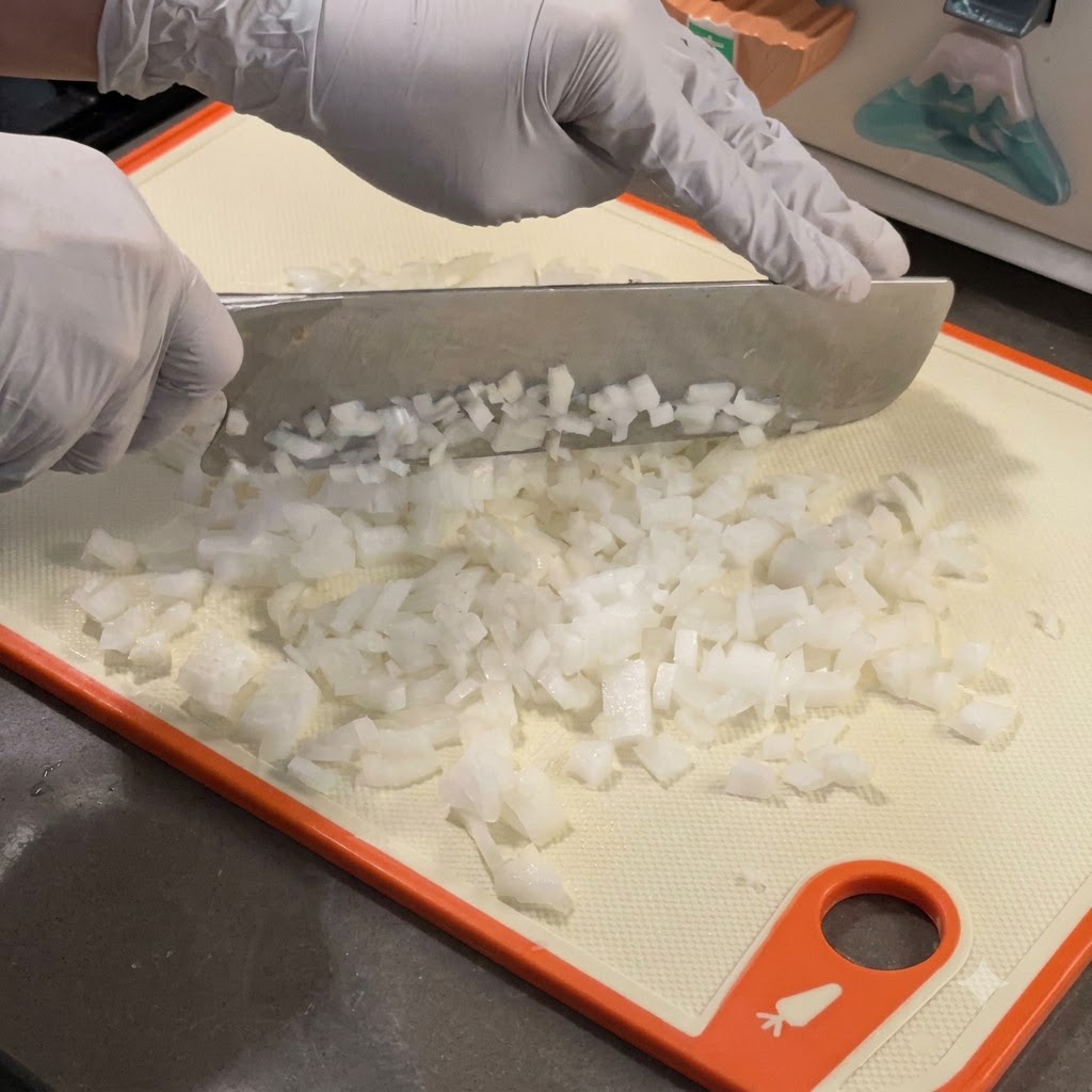 熱した鋳鉄製のスキレットで細かく刻んだ白い玉ねぎを炒めている様子。
