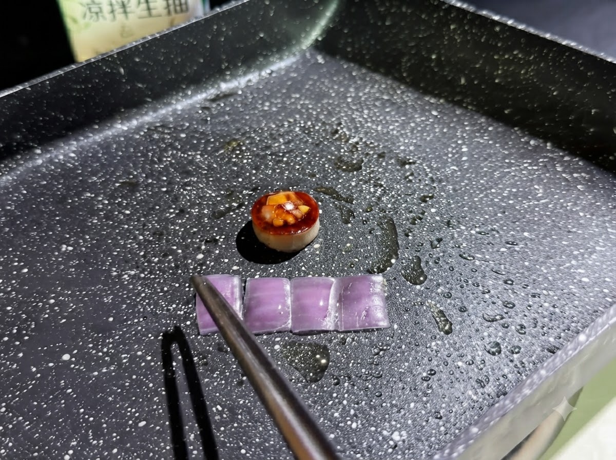 具材を入れたキノコリングの横で、紫玉ねぎの小さな長方形のスライス4枚が油を引いたフライパンで炒められている様子。