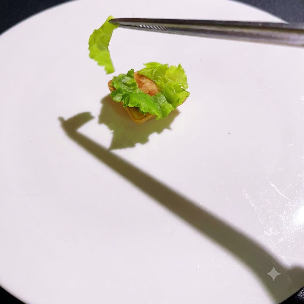 ピンセットを使って、調理された層がレタスベースの上に順番に積み重ねられている様子。