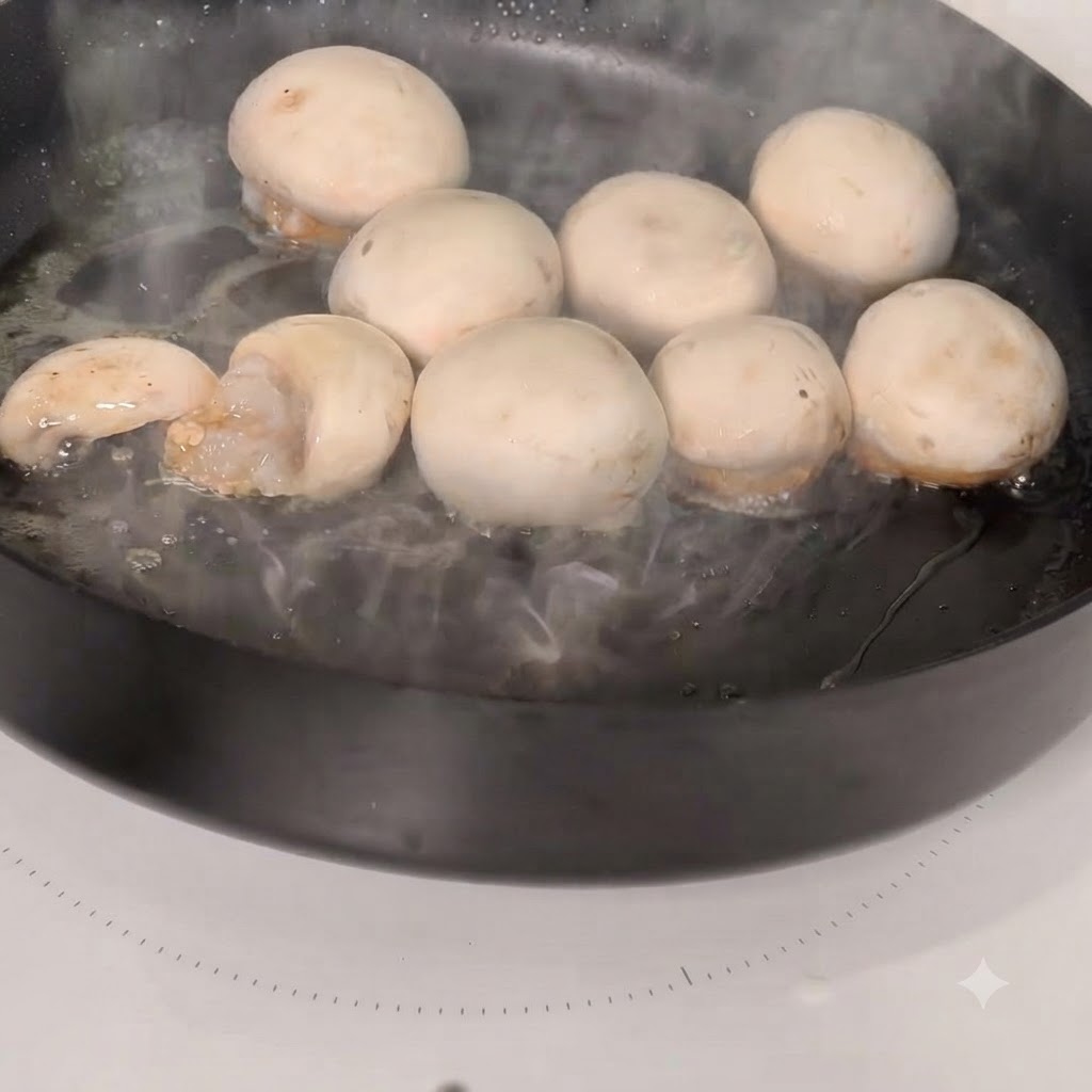 熱したスキレットで調理されるエビを詰めたマッシュルームの傘。