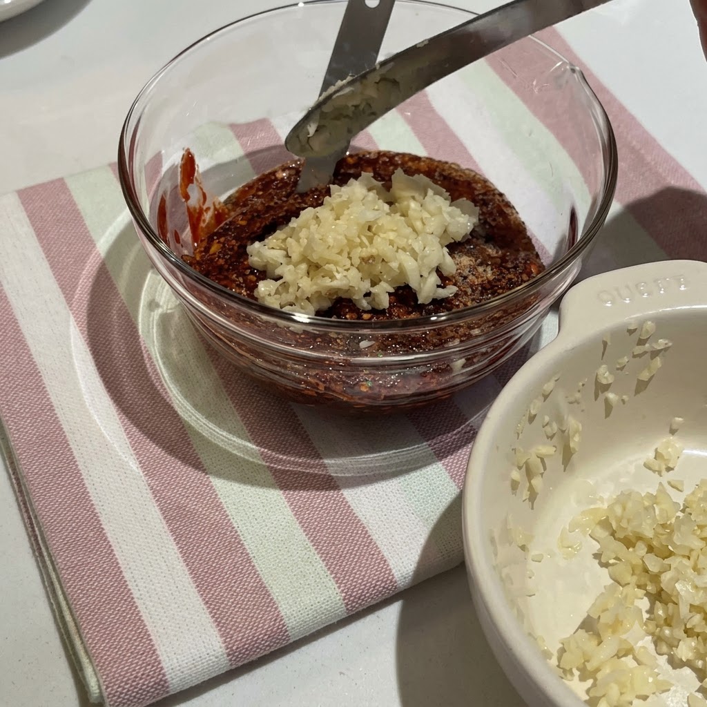 ガラスボウルの中でコチュジャンや様々な調味料が混ぜ合わさり、濃厚な赤いソースができている様子。