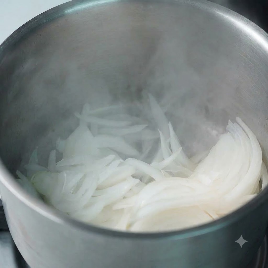 湯気が立ち上る温かい鍋に、スライスしたばかりの玉ねぎが入れられている様子。