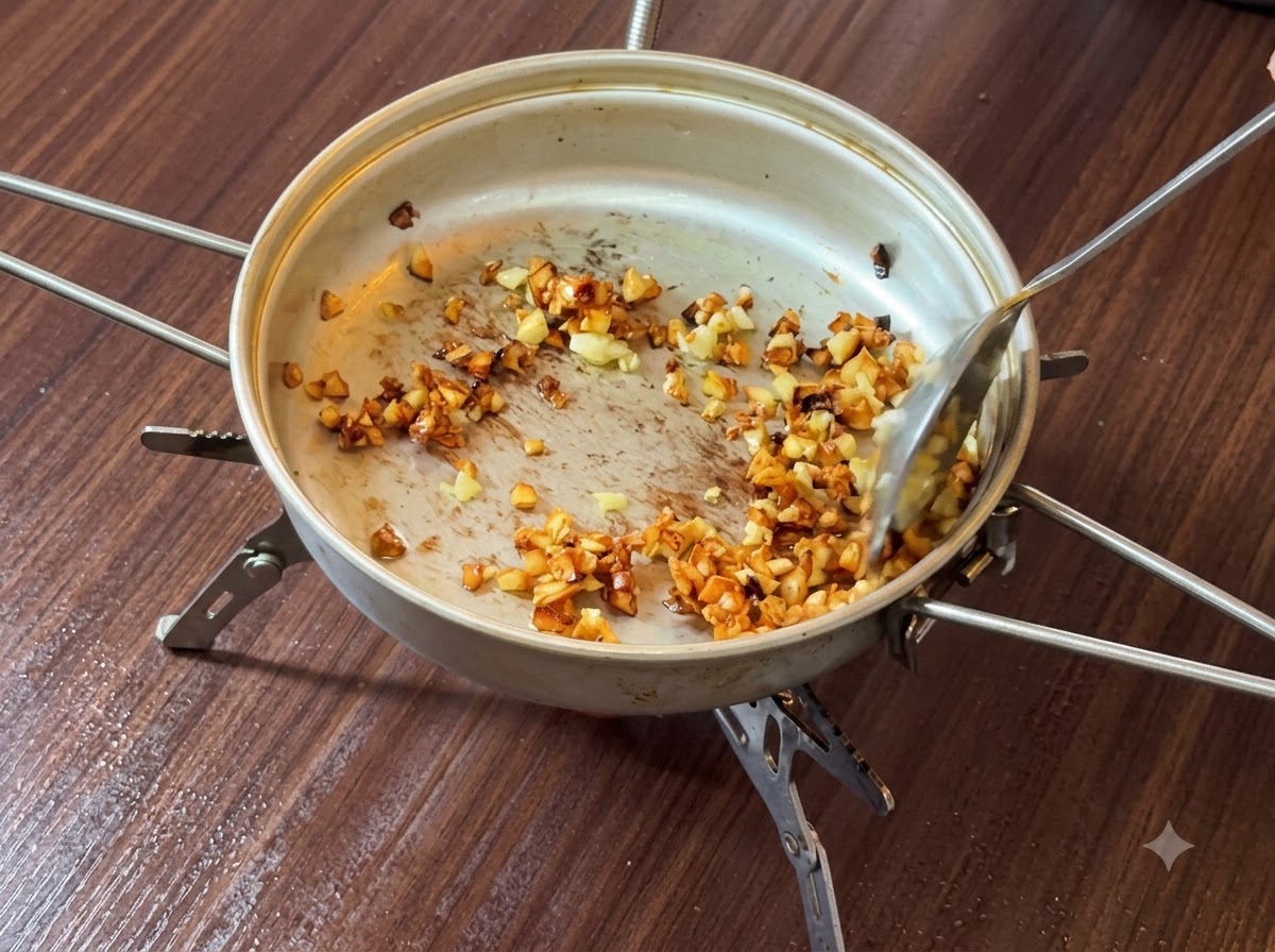 フライパンの中でバターとともに炒められ、きつね色から濃い茶色に変わっていくみじん切りニンニク。