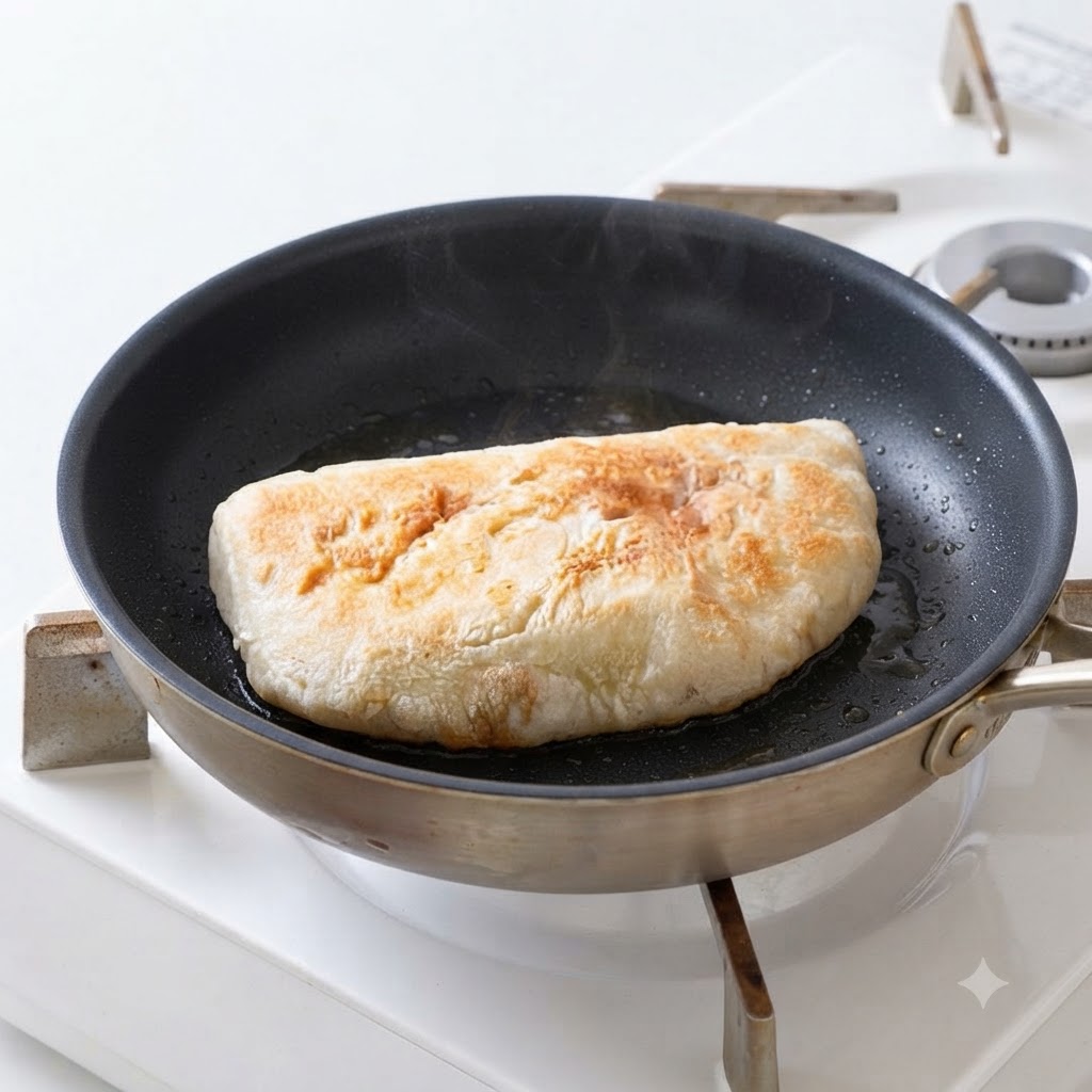フライパンで油を熱し、チャバタパンの断面をきつね色になるまで焼いている様子。