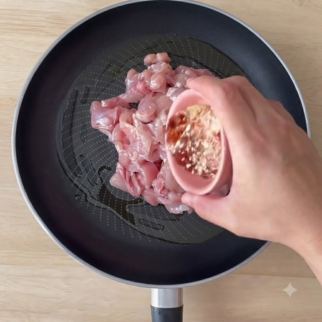 フライパンにオリーブオイルをひき、スパイスをまぶした鶏肉を炒めている様子。