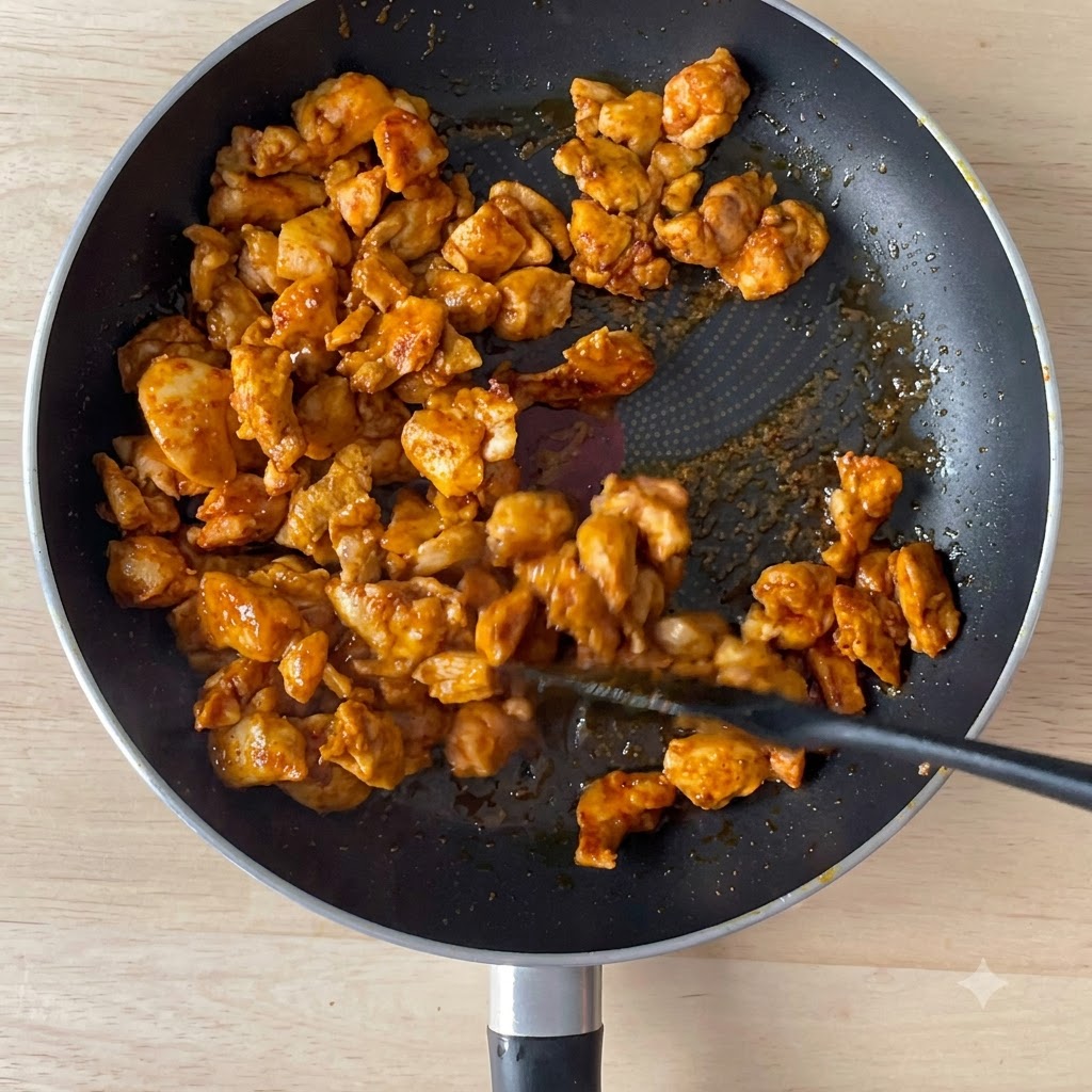 こんがり焼けた鶏肉が入ったフライパンに醤油を注いでいる様子。