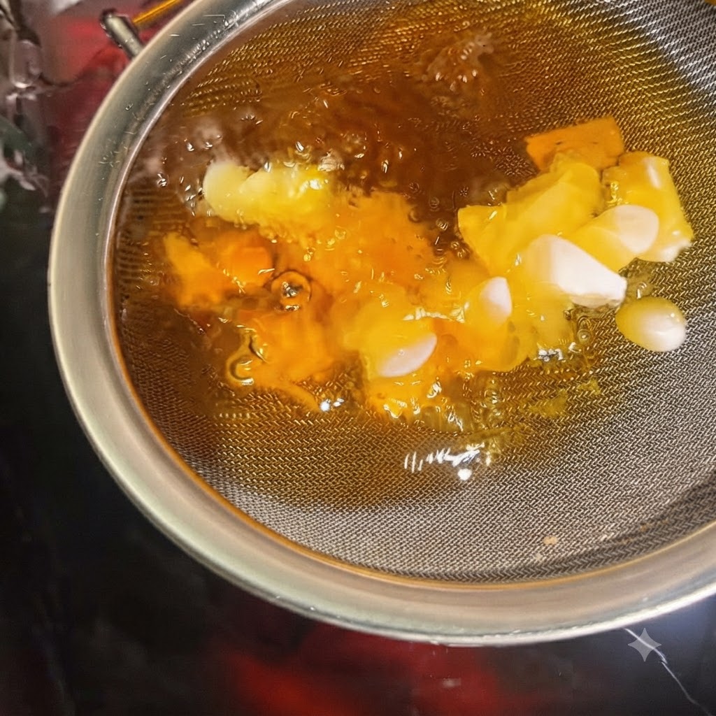 油に浸したザルの中で、ニンニクスライスがサクサクと黄金色に揚がっている様子。